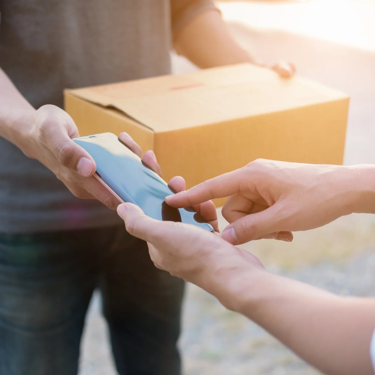 Man holding 3 boxes at home while looking at phone screen