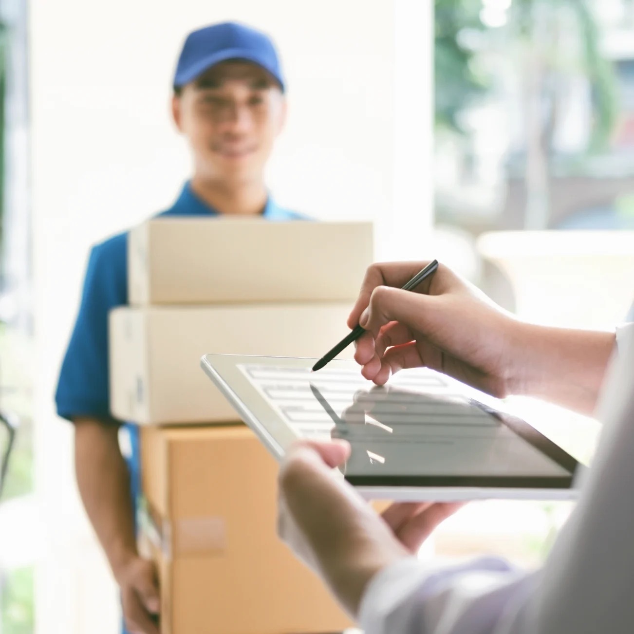 Man holding 3 boxes at home while looking at phone screen